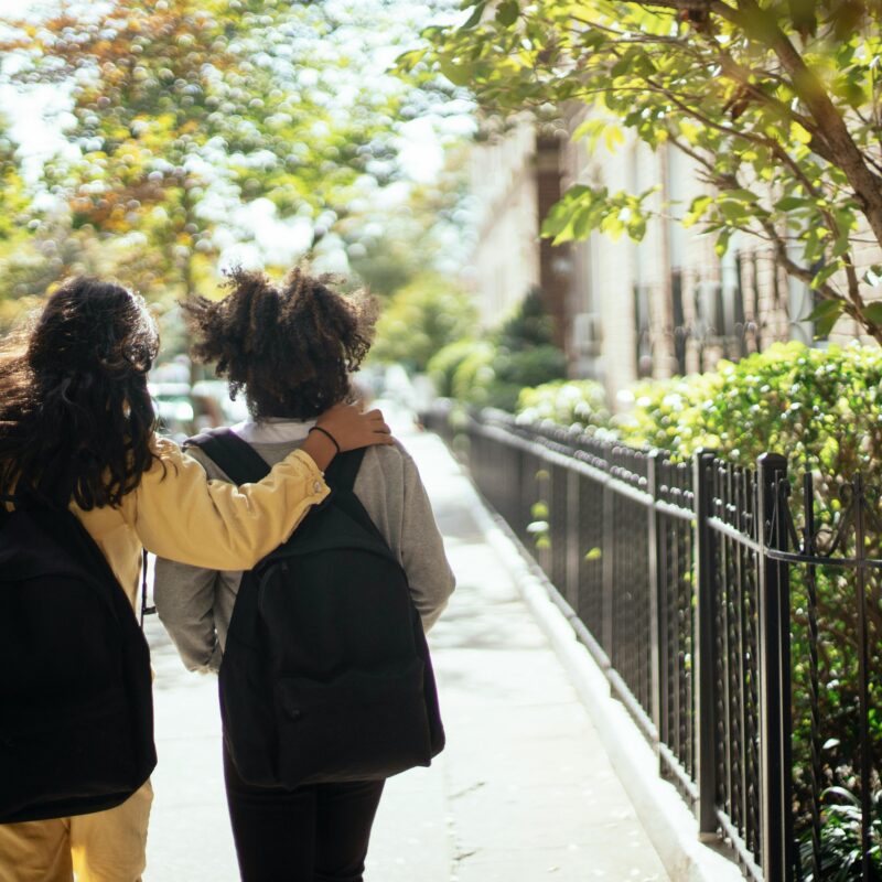 Teenage schoolgirls with backpacks walking together
